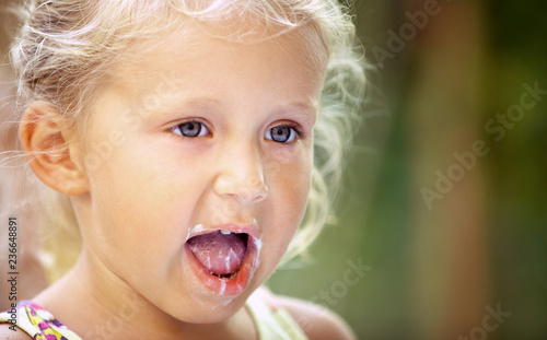 Cute little girl child with traces of ice cream on her face on a colorful background. Unique emotions close-up