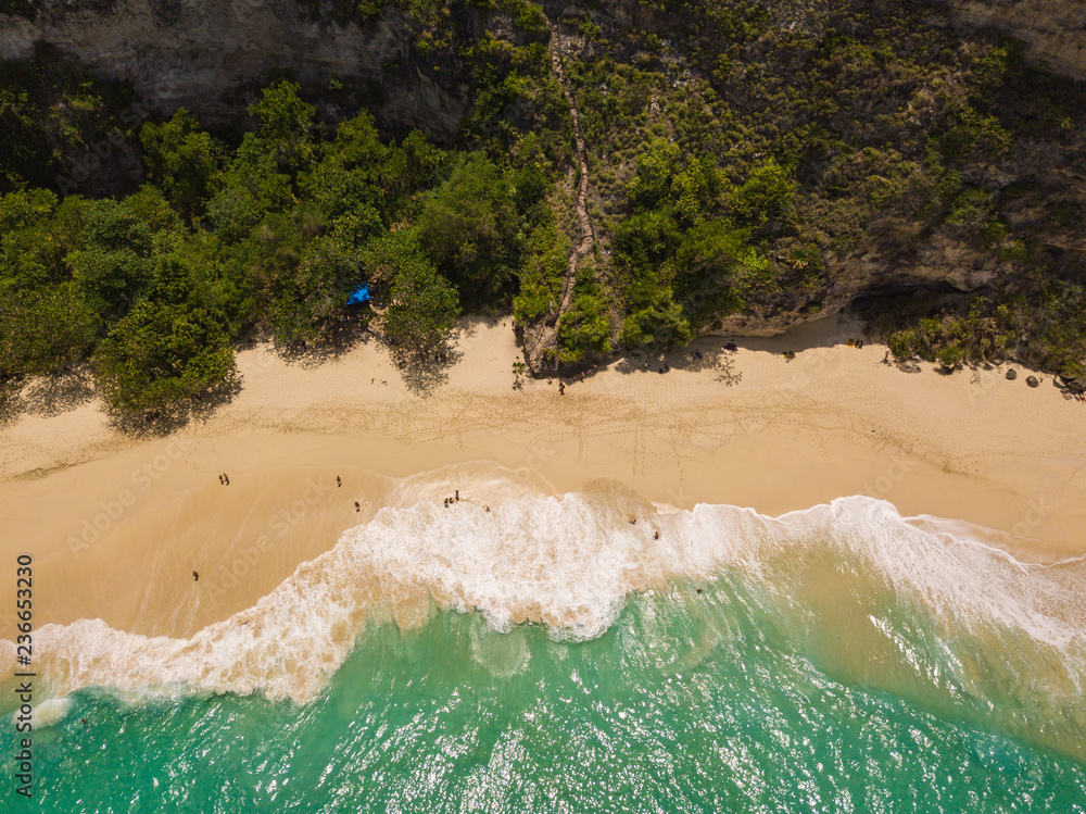 Aerial view of the Kelingking beach located on the Nusa Penida island. Turquoise water, white waves and clear sand. Photo from drone. Indonesia.