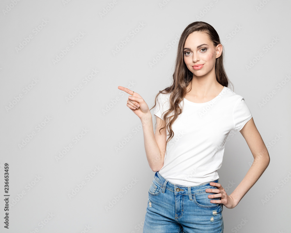 Studio portait of beautiful young woman pointing at copy space