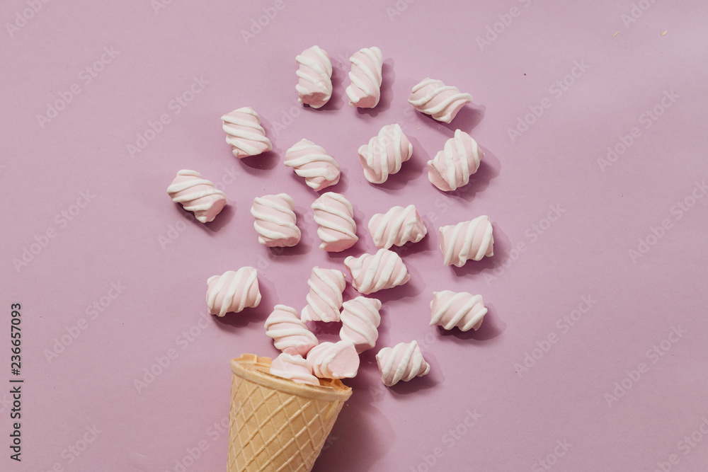 Crispy waffle cone with scattered marshmallows on purple background, food flat lay Crispy waffle cone with scattered marshmallows on purple background, food flat lay