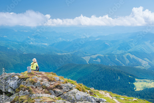 Wallpaper Mural Young woman sitting on mountains cliff Torontodigital.ca