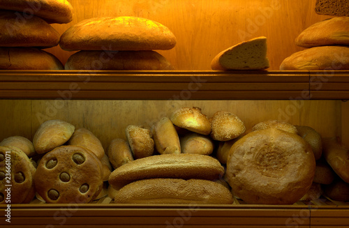 breads standing at baker shop case detail, yellow light, front view photo