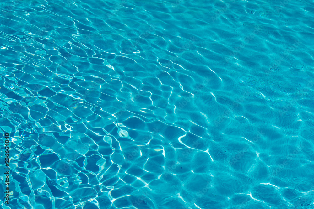 Blue water in swimming pool background. Ripple Water in swimming pool with sun reflection. Blue swimming pool rippled water detail