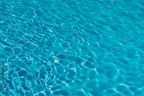 Blue water in swimming pool background. Ripple Water in swimming pool with sun reflection. Blue swimming pool rippled water detail © jollier_
