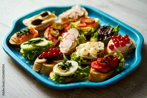 old blue tray with a set of healthy tapas or mini sandwiches on a light wooden table