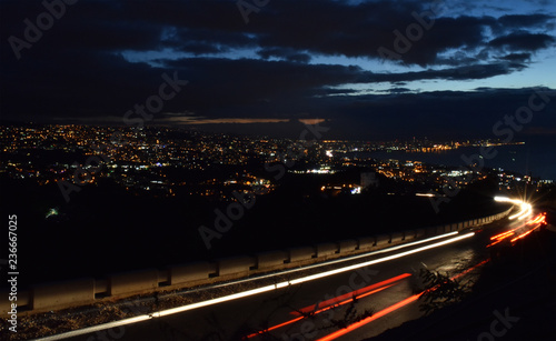 Big road with car lights in the night and Beirut bifg town in background, at dusk photo