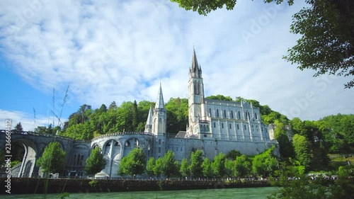 Scenic view of old catholic cathedral in small ancient historic town Lourdes and crown walking bank of river Pau. Beautiful clip about world pilgriamge center in south of France.