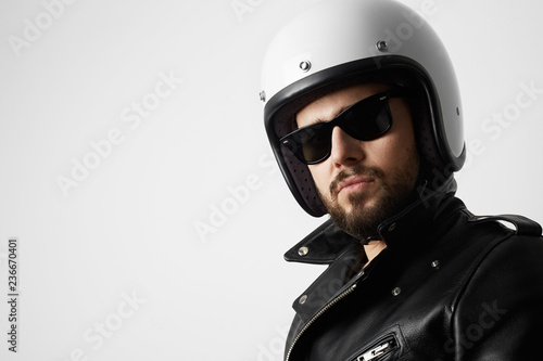 Close up portrait of smiling motorcyclist wearing helmet and leather jacket. Space for your text.