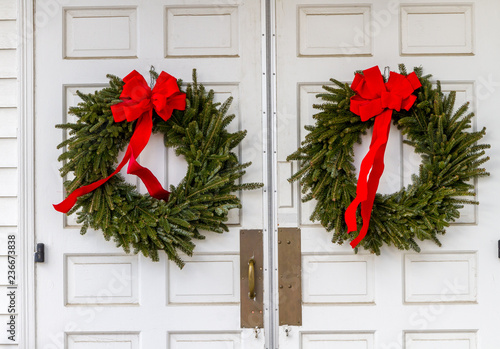 Two Christmas wreaths on white church door