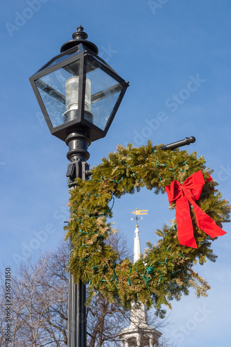 Christmas wreath on lamp post with church steeple in background