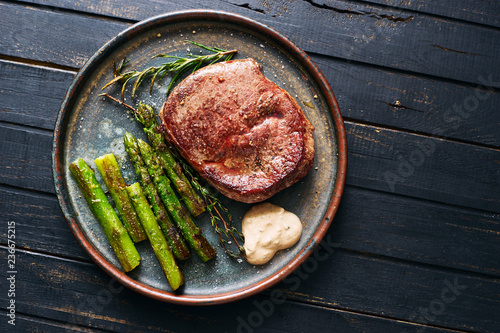 Hot homemade beef steak with herbs and grilled asparagus top view