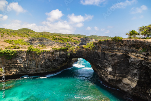 Stone arch over the sea. Beautiful and clear turquoise water at Broken Beach in Nusa Penida, Indonesia.