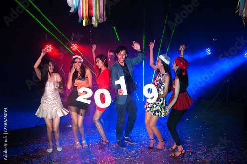Group of people dancing at night club with Santa hat Christmas holidays party friendship relaxing celebrating new year 2019.