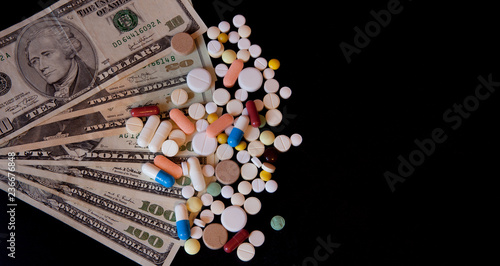 Pills on dollar money isolated on black background. Medicine expenses. High costs of medication concept photo