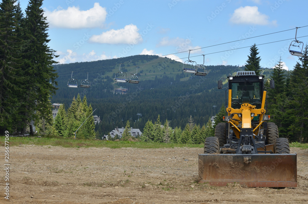 Digger vehicle in mountain with hills behind it Digger vehicle in mountain with hills behind it