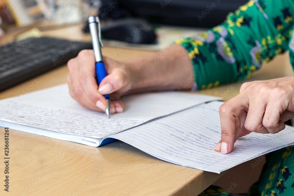 Female hand writing on a paper - notebook on a desk at office. Female hand writing on a paper - notebook on a desk at office.