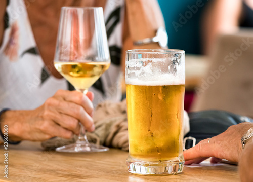 Hands of a couple having beer and white wine sitting in a table outdoors a bar in Spli, Croatia.