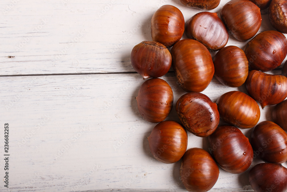 pile of sweet chestnuts on white wooden background pile of sweet chestnuts on white wooden background