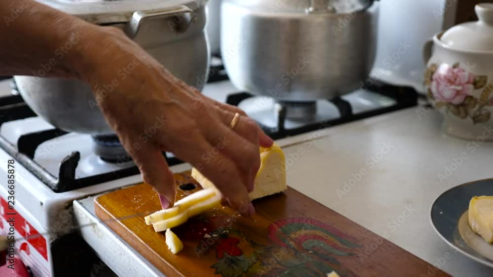 Woman's hand chopping homemade yellow fresh milk cheese traditional to ...