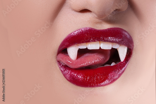 Sexy vampire. Women s lips with red lipstick. Tongue licking vampire fangs