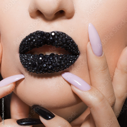 Black lips covered with rhinestones. Beautiful woman with Black lipstick on her lips and black and white manicure photo