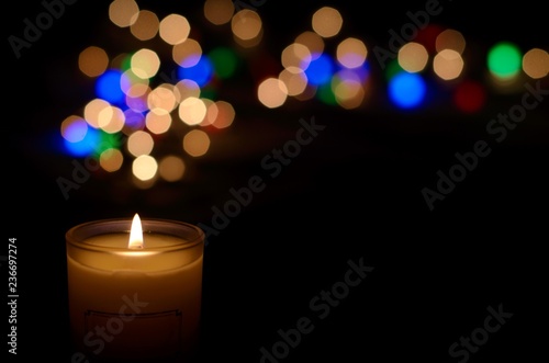 Candle with flame and bokeh light in dark background for praying in Church concept.