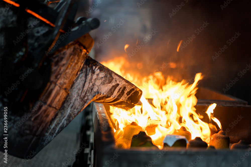 Fototapeta premium Molten metal casting, operator pouring metal casting parts from ladle in factory