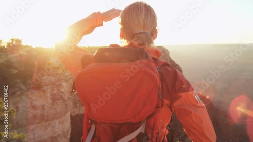 Caucasian female hiker motivated by her successful achievement viewing Grand Canyon sun flare sunset Arizona USA 