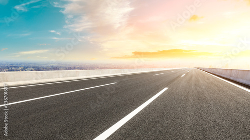 Panoramic city skyline and buildings with empty asphalt road at sunset