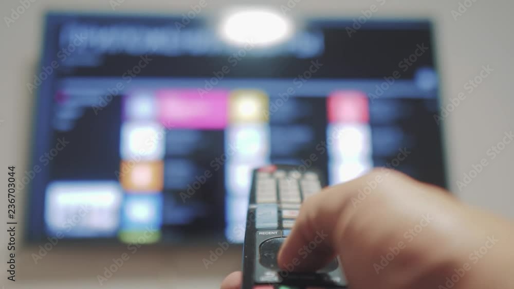 Smart tv with apps and hand. Male hand holding the remote control turn off smart tv . man hand controls TV holding remote. lifestyle TV concept internet online cinema Smart tv with apps and hand. Male hand holding the remote control turn off smart tv . man hand controls TV holding remote. lifestyle TV concept internet online cinema