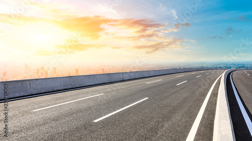 Panoramic city skyline and buildings with empty asphalt road at sunset