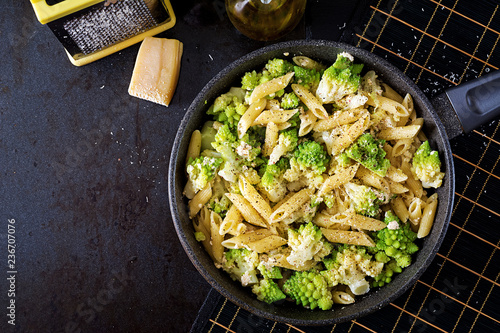 Penne pasta with cabbage romanesco on black table. Vegetarian food. Italian menu. Top view. Flat lay photo