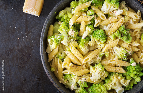 Penne pasta with cabbage romanesco on black table. Vegetarian food. Italian menu. Top view. Flat lay photo