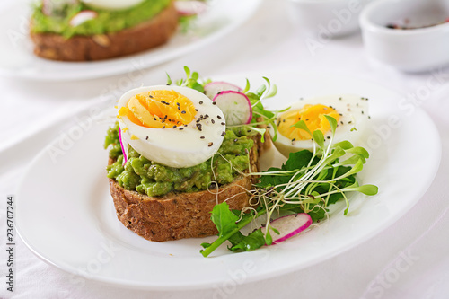 Healthy food. Breakfast. Avocado egg sandwich with whole grain bread on white wooden background.