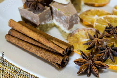 Lie on a plate of cakes, a lemon slices with star anise and cinnamon sticks.