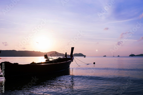 fishing boat or longtail boat in the sea in morning time with beautiful sunrise and reflection in the water at phuket andaman sea thailand