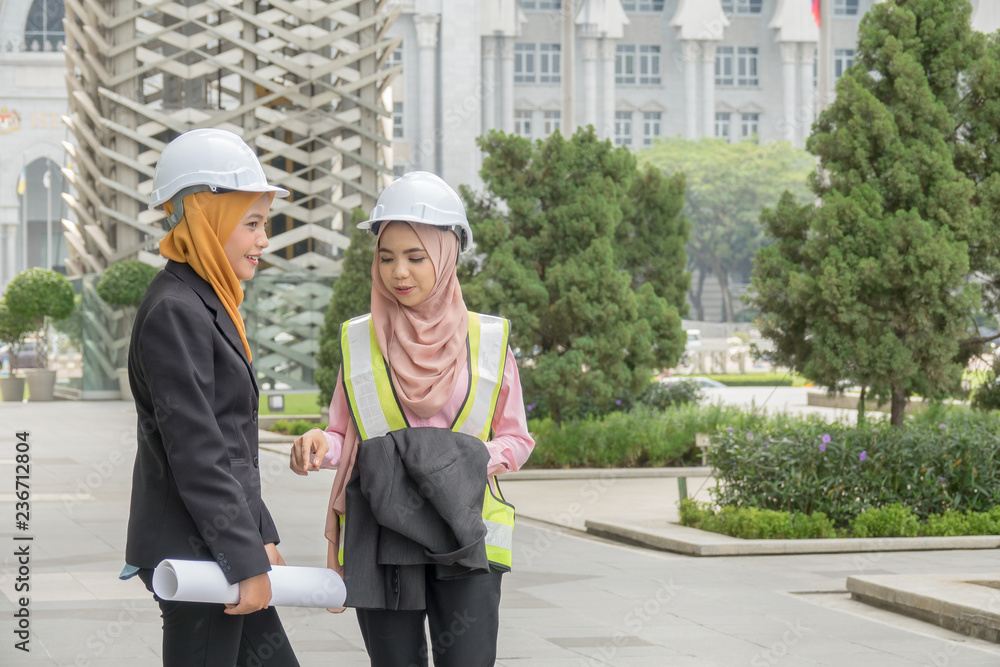 Professional woman engineers are discussing on construction at outdoor.