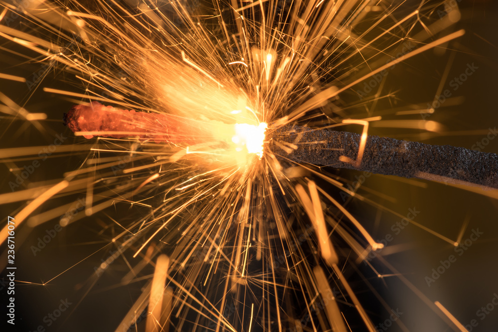 Fototapeta premium Burning sparkler close up on a black background, a lot of sparks