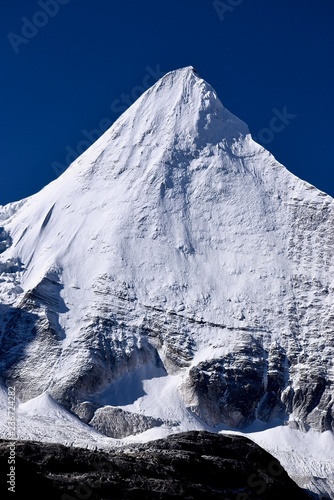 Sharp summit of the sacred mountain Jambeyang (5,958m) with blue sky background. Daocheng Yading Nature Reserve, Sichuan, China. 