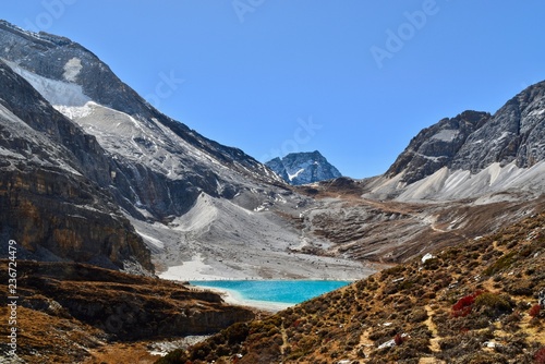 Unique colored Milk lake (approx. 4300m altitude) with blue sky and sharp mountains around it in Daocheng Yading Nature Reserve, Sichuan, China.   photo