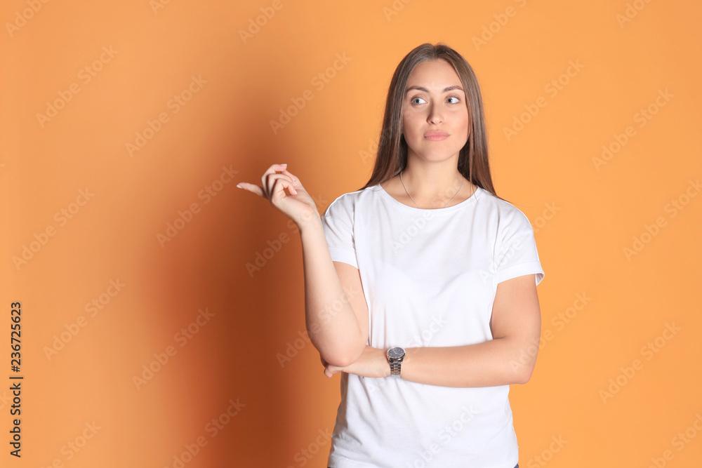 Young woman in basic clothing smiling and pointing finger at copyspace isolated on yellow background. Young woman in basic clothing smiling and pointing finger at copyspace isolated on yellow background.