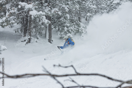 man skier free rider goes down on powder snow in the mountains in a snowfall