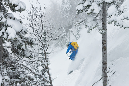 Free rider skier jumps from a springboard of snow in trees in the mountains