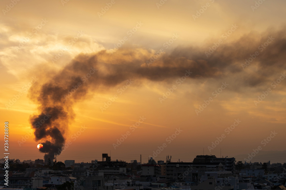 Fototapeta premium Black smoke from structure fire in Osaka neighborhood billows into setting sun