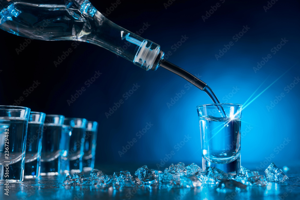 Vodka poured into a glass lit with blue backlight. Vodka poured into a glass lit with blue backlight.