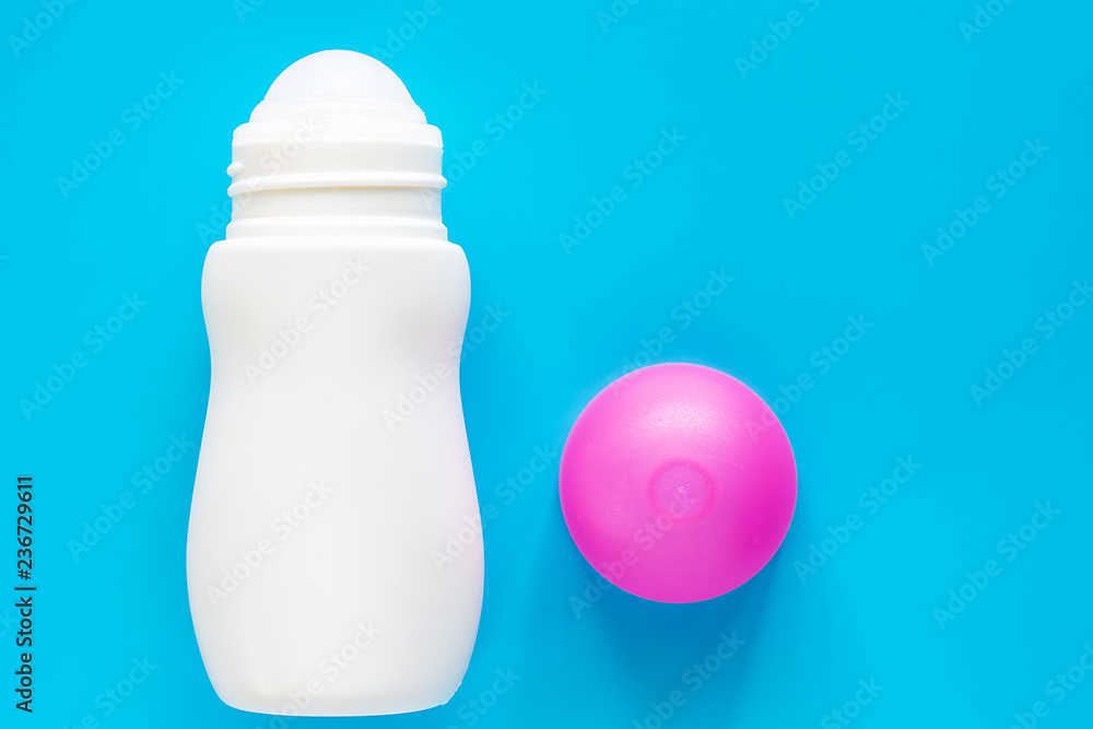 Female deodorant or roll on bottle with pink cover on blue background for body skin care concept