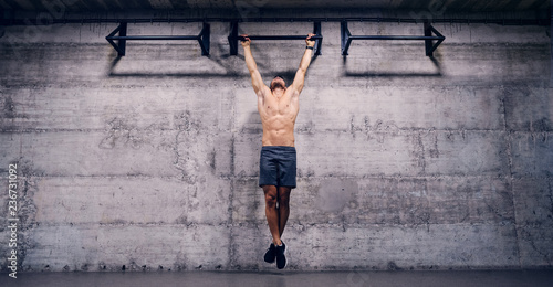 Shirtless man doing pull ups in the gym. When you lose all excuses, you'll find results. photo