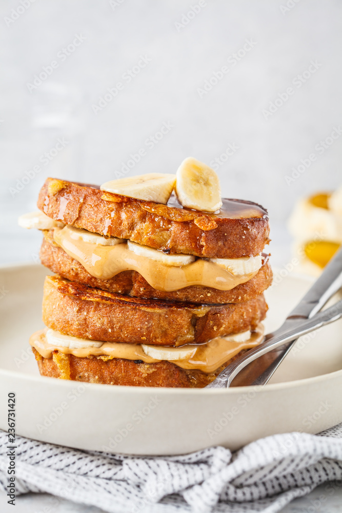 French toasts with peanut butter and banana on a white plate. French toasts with peanut butter and banana on a white plate.