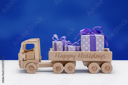Wooden toy truck with gifts in boxes decorated with ribbons and bows.