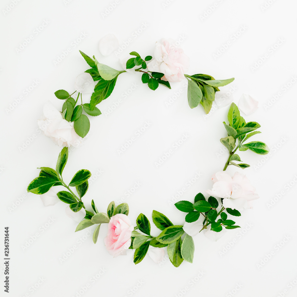 Naklejka premium Floral round frame of roses and green leaves on white background. Flat lay, top view. Spring time composition